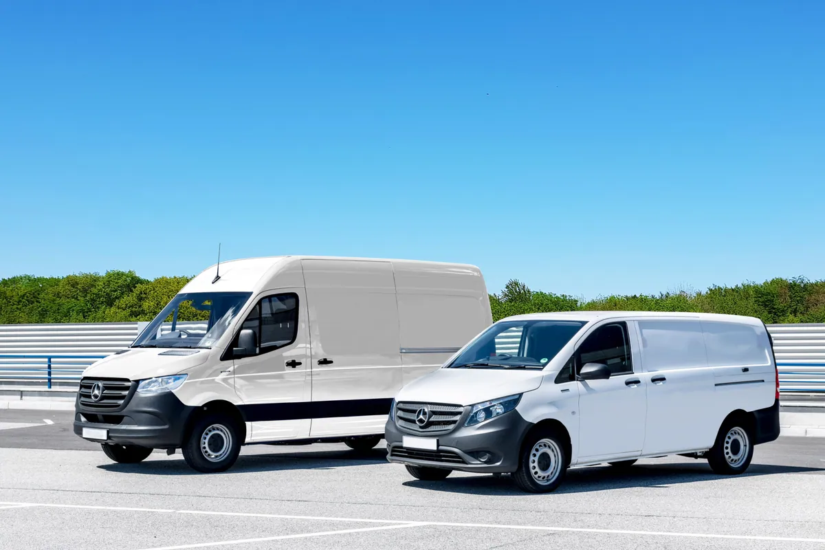 Two white cargo vans parked side by side in a paved lot